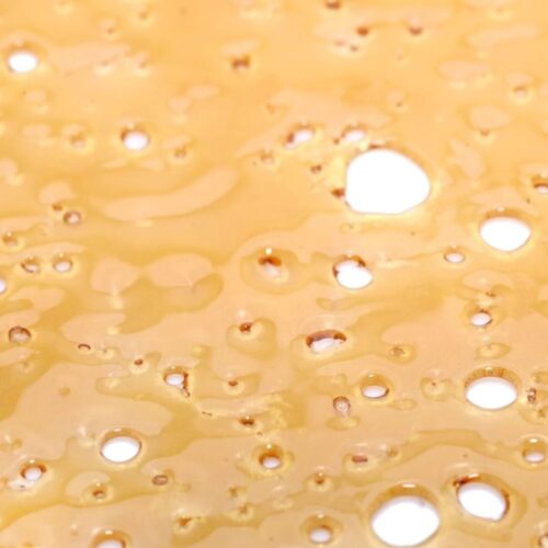 A close-up of Cinderella 99 Hybrid Shatter, showcasing its golden, translucent texture with a crisp, glass-like break. Ideal for dabbing, vaping, or enhancing flower.