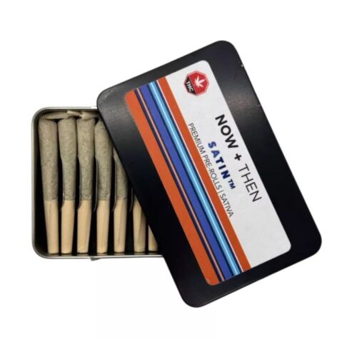 Half-open tin of Now + Then SATIN Sativa Pre Roll 12 Pack – Snow Drop, revealing several slim 0.5g pre rolls inside with clean citrus-floral packaging design