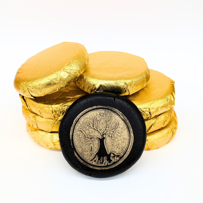 An image of black hash wrapped in gold foil with other coins of hash